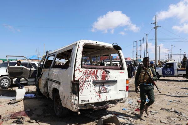 Policial somali ao lado de um veículo atingido pelo atentado (Imagem:Feisal Omar/Reuters)