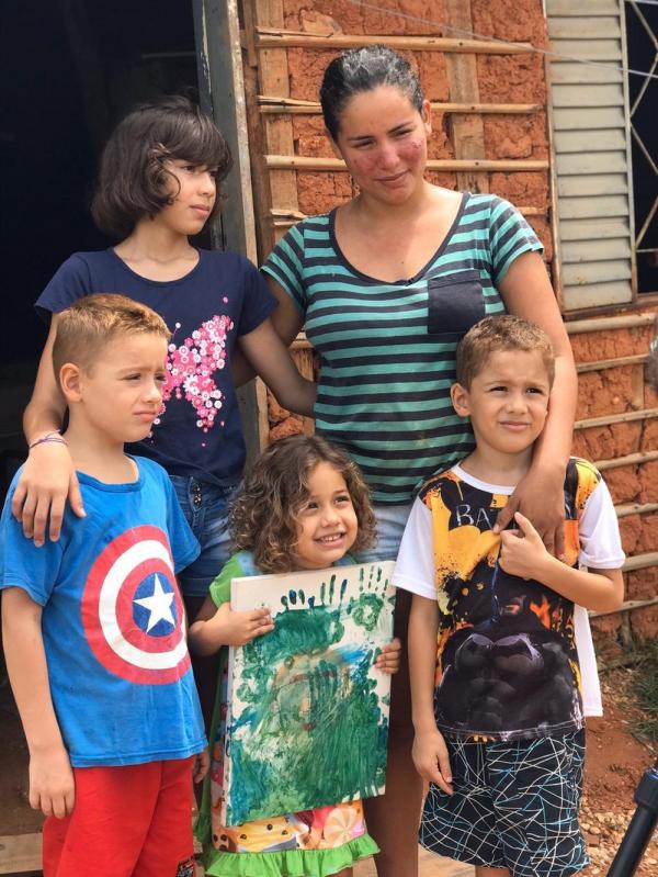 Thais e os filhos com o quadro feito por Luna, na porta de casa(Imagem:Neyara Pinheiro/TV Clube)