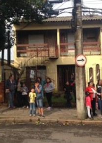 Vizinhos de Patrícia Moreira observam casa que foi incendiada.(Imagem:Paula Menezes/GloboEsporte.com)