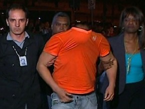 Macarrão escondeu o rosto ao descer do carro da polícia (Imagem:Reprodução/Globo News)