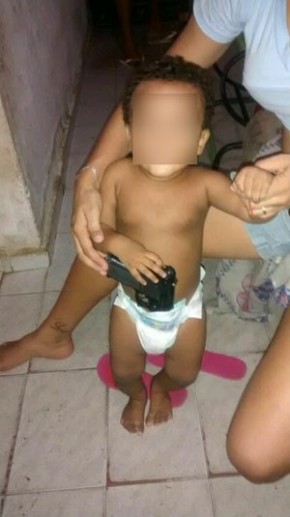 Criança aparece nas fotos segurando arma.(Imagem:Divulgação/Polícia Civil)