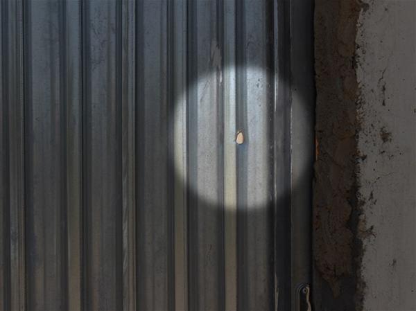Marca de tiro ficou no portão da casa onde a vítima trabalhava e morava.(Imagem:Juliana Barros/G1)