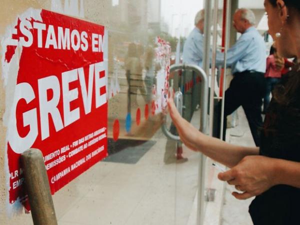 Funcionária retira adesivo referente a greve com o fim da paralisação.(Imagem:Marcelo Brandt/G1)