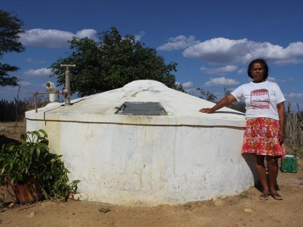 Maria Francisca ao lado da cisterna que armazena a água levada pelo carro-pipa.(Imagem:Patrícia Andrade/G1)