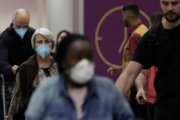 Pessoas usam máscara em terminal de aeroporto no Rio de Janeiro: país já tem 14 casos confirmados(Imagem:Ricardo Moraes/Reuters)