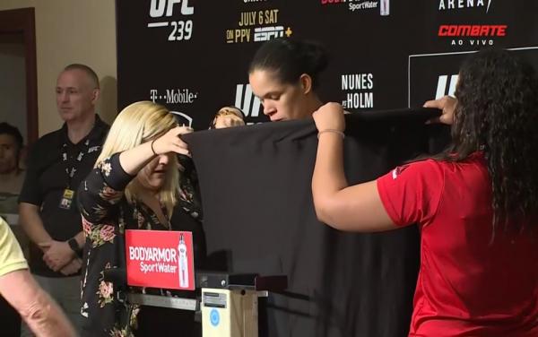 Nua dentro do biombo, Amanda Nunes olha para baixo enquanto o comissário não anuncia seu peso.(Imagem:Reprodução)