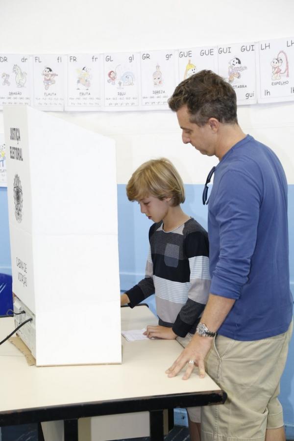 Joaquim ajuda o pai a votar.(Imagem:Felipe AssumpçãoAgNews)