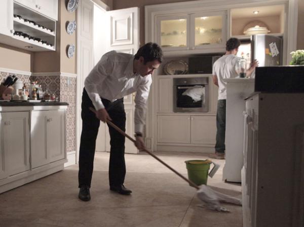 Léo limpa o chão da cozinha, quando Ismael chega.(Imagem:Insensato Coração / Tv Globo)