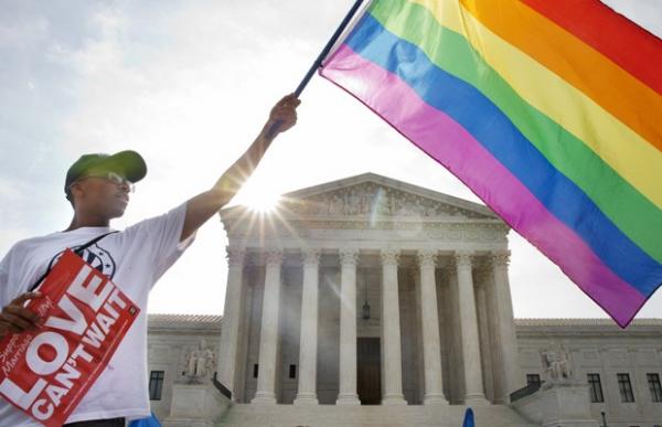 Ativista Carlos McKnight levanta bandeira do movimento GLBT em frente à Suprema Corte em Washington, nesta sexta (26).(Imagem:Jacquelyn Martin/AP)