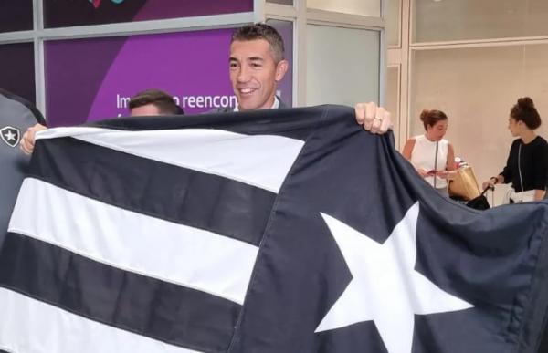 Bruno Lage posa com bandeira do Botafogo na chegada ao Rio.(Imagem:Ronald Lincoln)