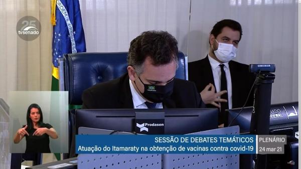 Assessor especial de Bolsonaro, Filipe Martins (ao fundo), faz gesto com a mão durante sessão do Senado.(Imagem:Reprodução/TV Senado)