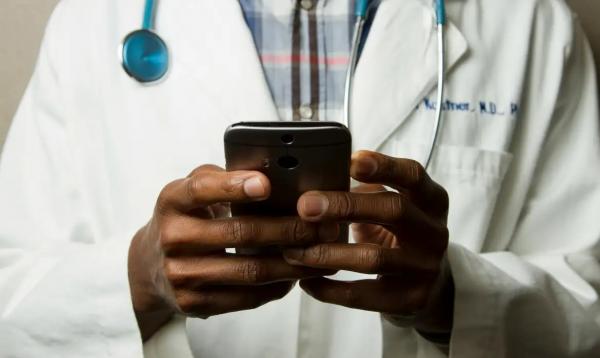Médico com estetoscópio fala no celular.(Imagem:National Cancer Institute/Unsplash)