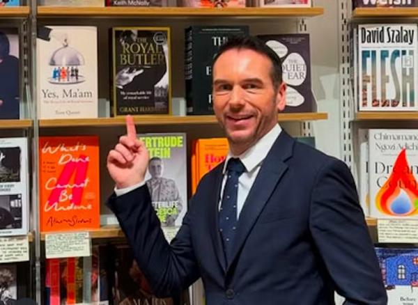 O ex-mordomo da Família Real Britânica, Grant Harrold, mostrando seu livro de memórias.(Imagem:Instagram)
