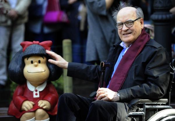 O cartunista Joaquin Salvador Lavado, também conhecido como Quino, posa ao lado de uma escultura de sua personagem Mafalda, em Oviedo, na Espanha. Foto de outubro de 2014.(Imagem:Miguel Riopa/AFP/Arquivo)