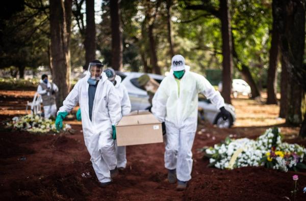 Funcionários vestindo roupas de proteção contra o coronavírus sepultam vítima da Covid-19.(Imagem:Werther Santana/Estadão Conteúdo)